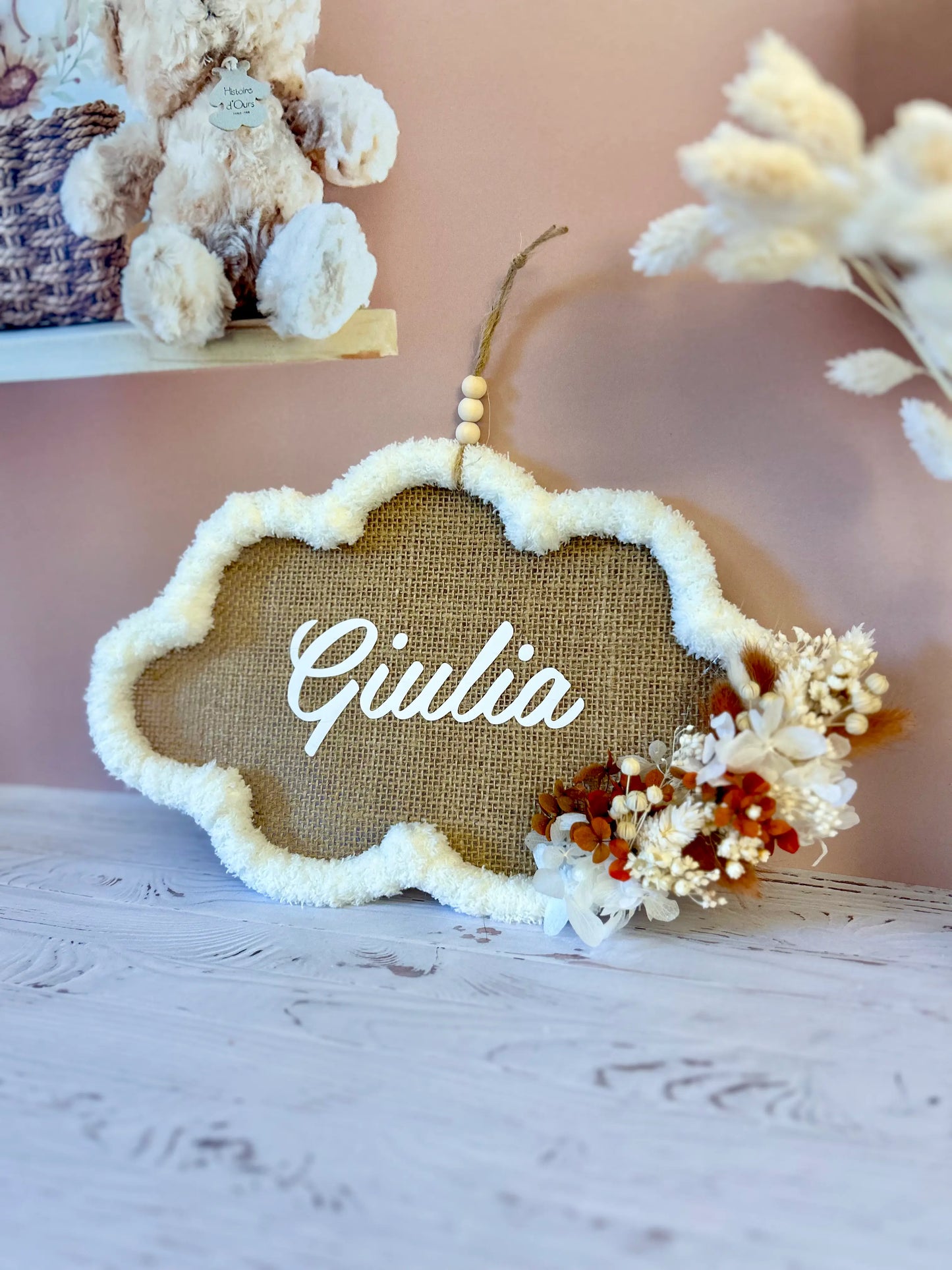 Vue du cadre nuage grand format suspendu, parfait pour une décoration de chambre de bébé personnalisée et élégante, avec des fleurs séchées dans des teintes naturelles et chaleureuses.