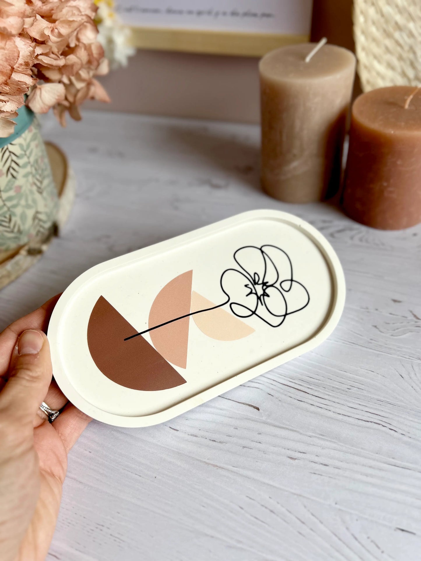 Zoom sur le motif fleur en vinyle noir du plateau décoratif ovale en jesmonite.