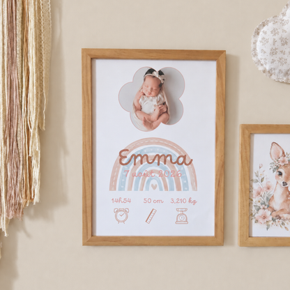 Affiche de naissance encadré avec thème arc-en-ciel rose pastel et terracotta, présentée dans une chambre de bébé sur un mur beige lin