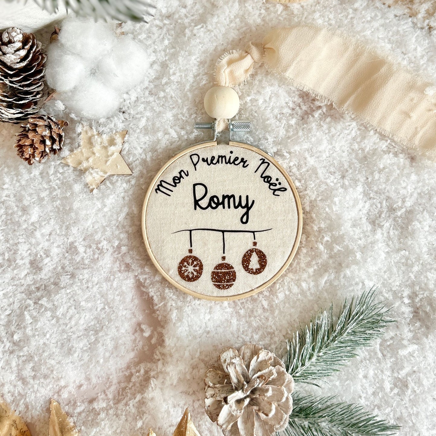 Boule de Noël personnalisée avec le prénom de bébé, posée dans la neige, à offrir en cadeau de naissance.