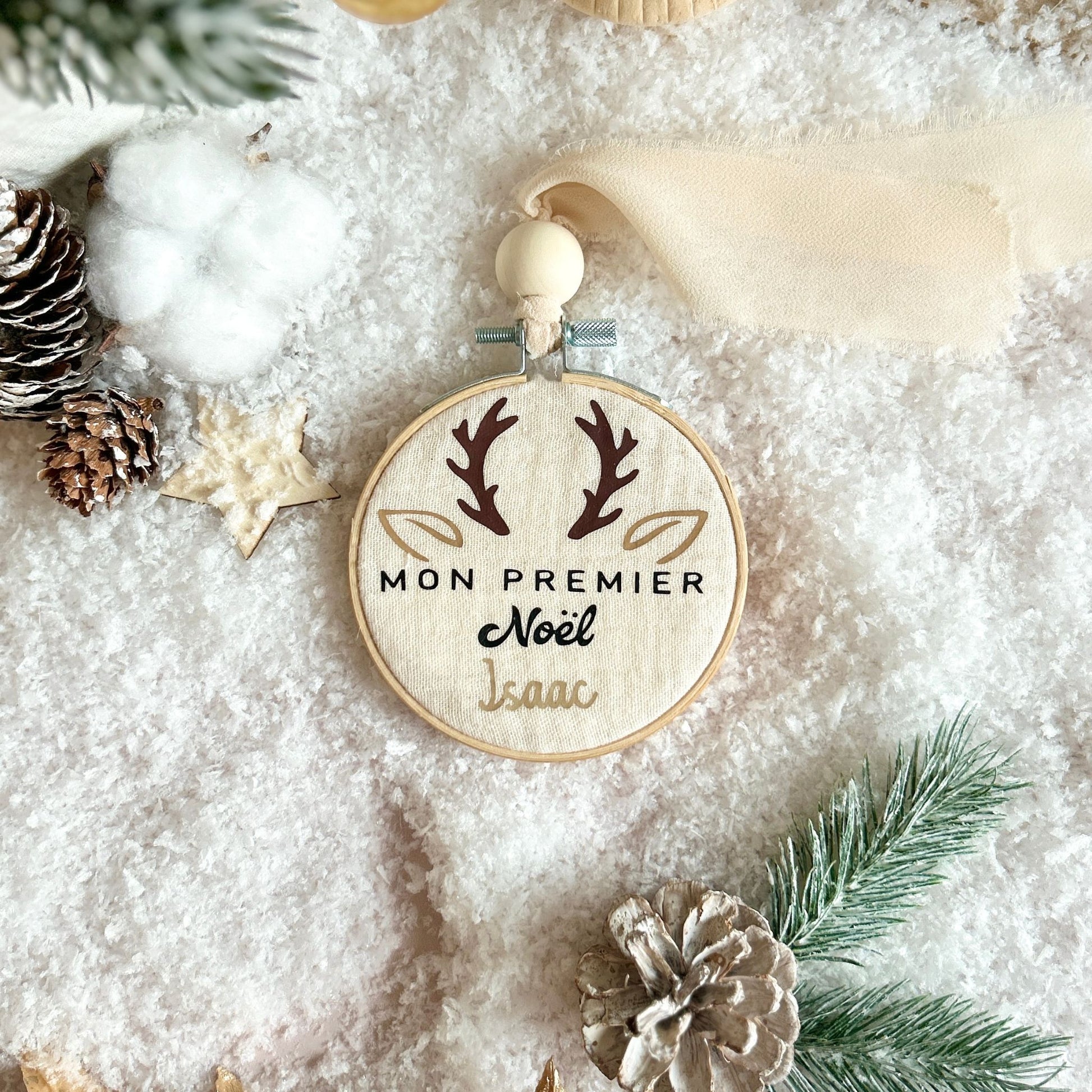 Boule de Noël faite main, déposée dans la neige et personnalisée avec le prénom de bébé pour célébrer son premier Noël.
