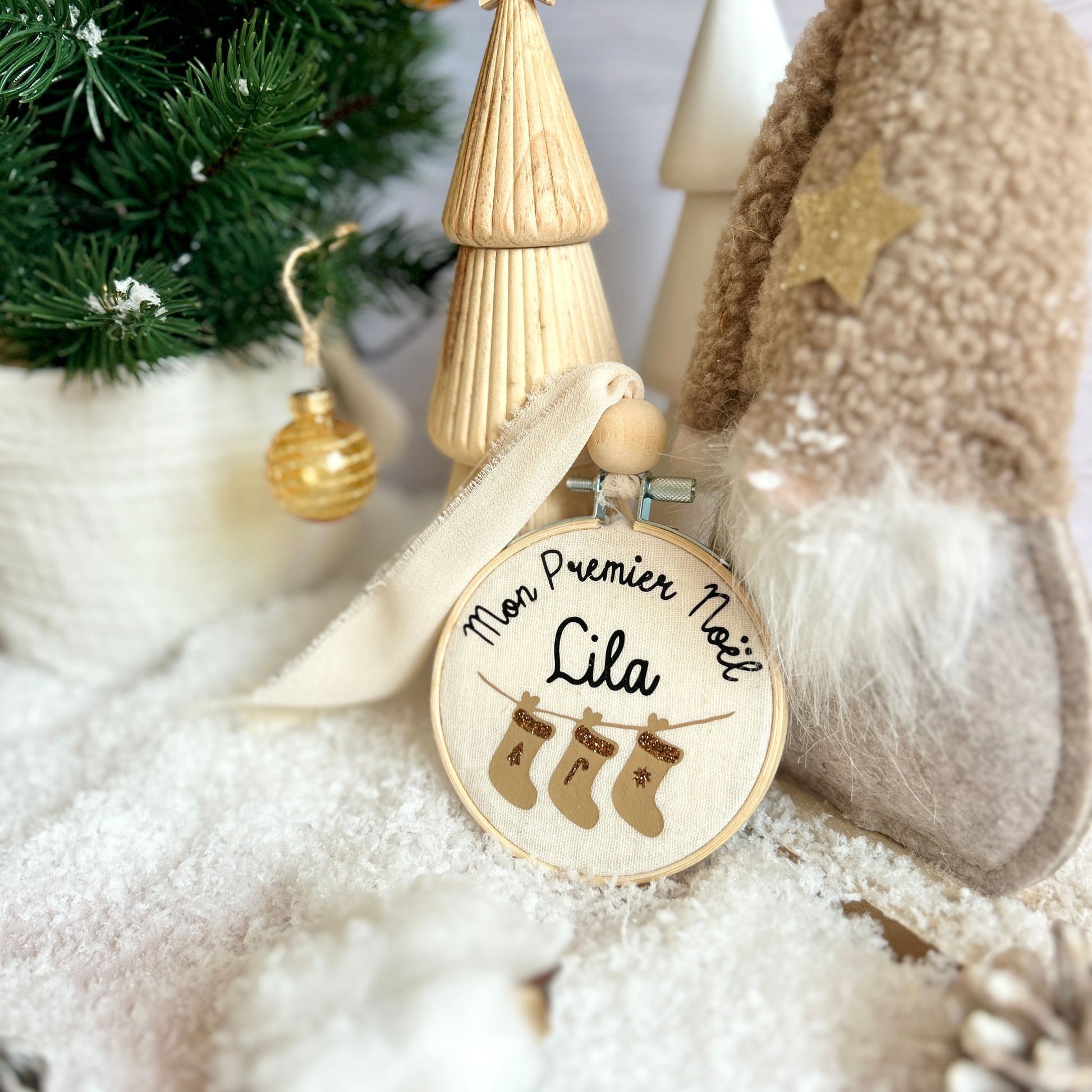 Boule mon premier Noël déposée dans un décor de neige au pied du sapin, à offrir en cadeau de naissance personnalisé avec le prénom de bébé.