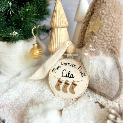 Boule mon premier Noël déposée dans un décor de neige au pied du sapin, à offrir en cadeau de naissance personnalisé avec le prénom de bébé.
