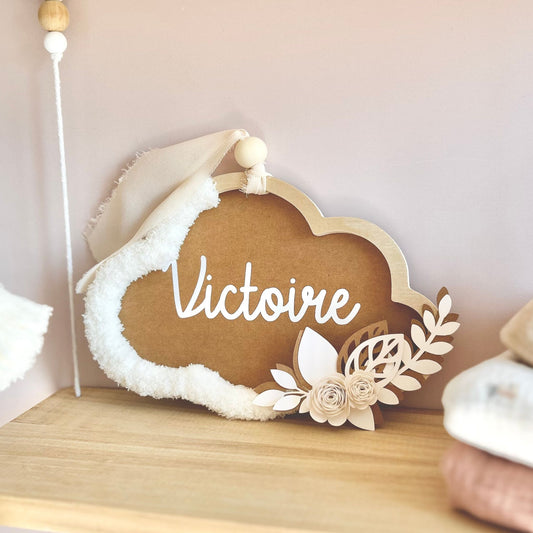 Cadeau de naissance personnalisé pour bébé fille, nuage mural marron et écru avec prénom, posé sur une étagère de chambre d'enfant.