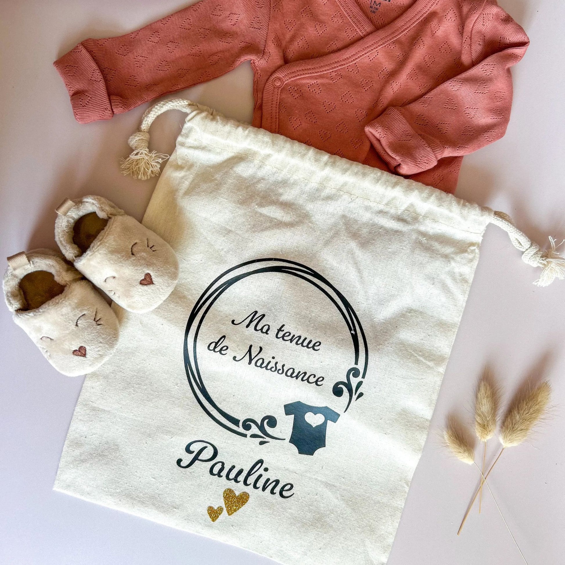 Sac en coton bio, à glisser dans le sac de maternité pour ranger la tenue de naissance de bébé. Le pochon est personnalisable avec le prénom de l'enfant.