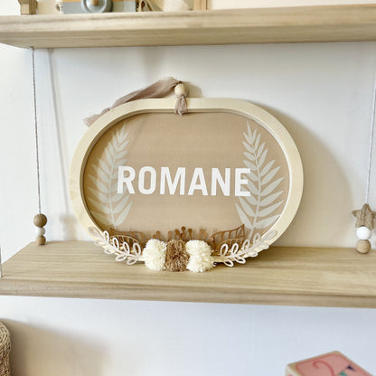 Cadre ovale personnalisé avec le prénom en bois naturel, décoration chambre bébé bohème aux tons beige sable et camel doux.