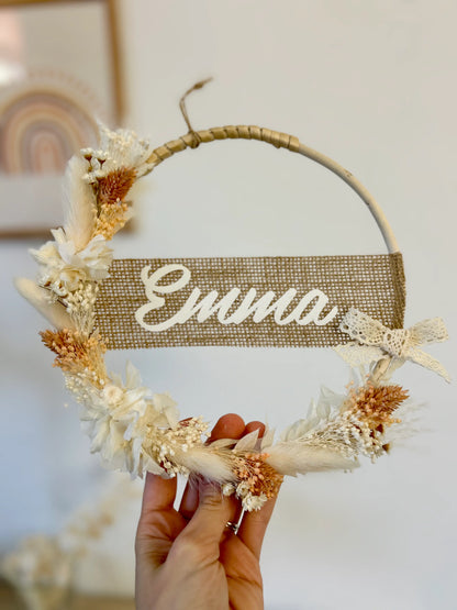 Vue d'ensemble de la couronne bohème avec les fleurs séchées et personnalisée avec le prénom de bébé, cadeau de naissance idéal et artisanal.