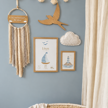 décoration chambre de bébé avec au centre du mur l'affiche de naissance personnalisable Petit Polisson, un attrape-rêves beige, un nuage en tissu et une illustration aquarelle représentant un phare marin