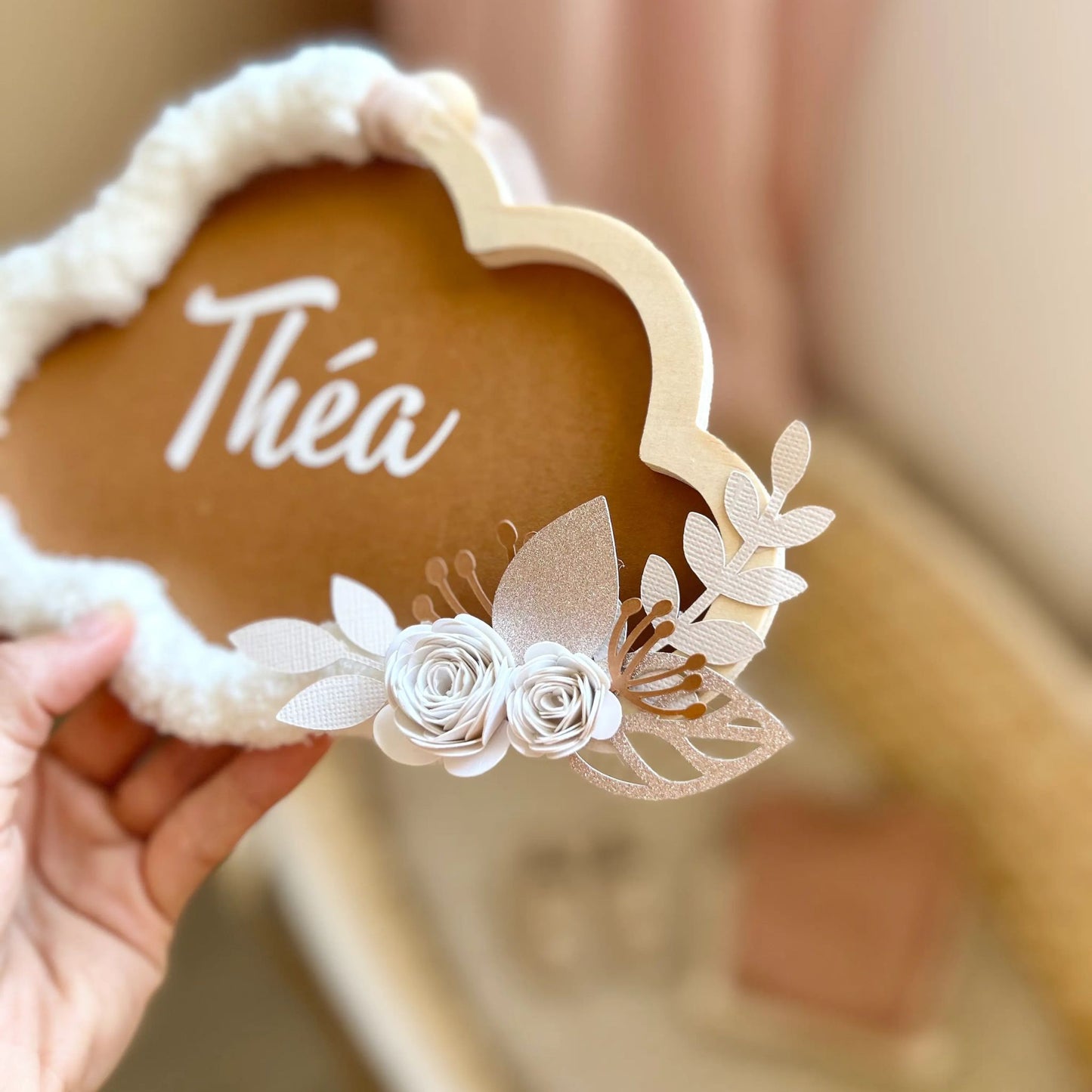 Détail des fleurs qui décorent la suspension murale en forme de nuage pour la décoration de la chambre d'un bébé fille.