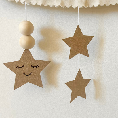 Détail des étoiles suspendues et perles en bois sous le nuage mural personnalisé bébé