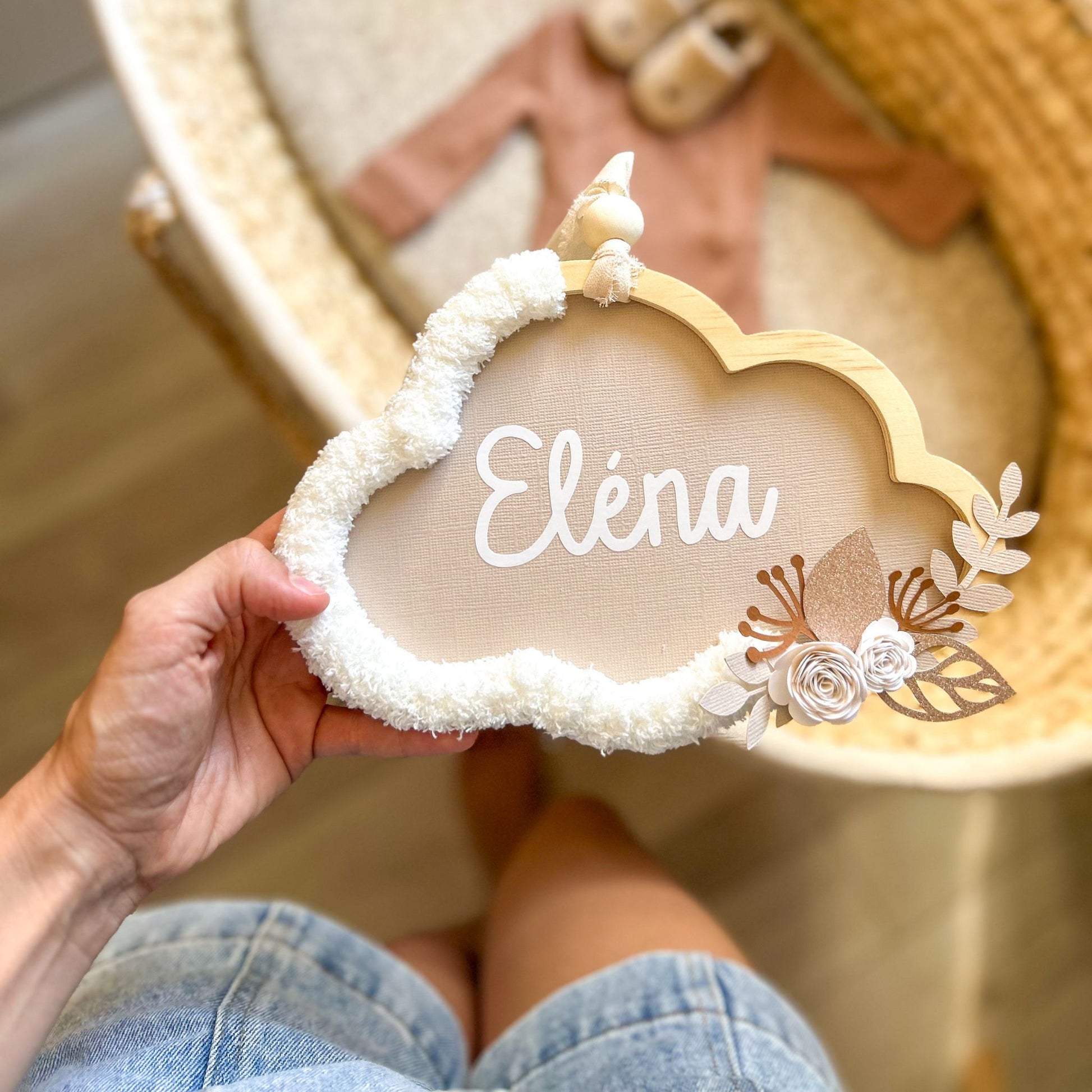 Détail du prénom personnalisé en vinyle découpé et posé main sur un nuage décoré de laine écru et fleurs beiges Petit Polisson.