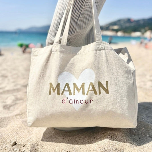 Grand cabas maman d’amour en coton naturel posé en extérieur, sac simple et élégant pour toutes les occasions.