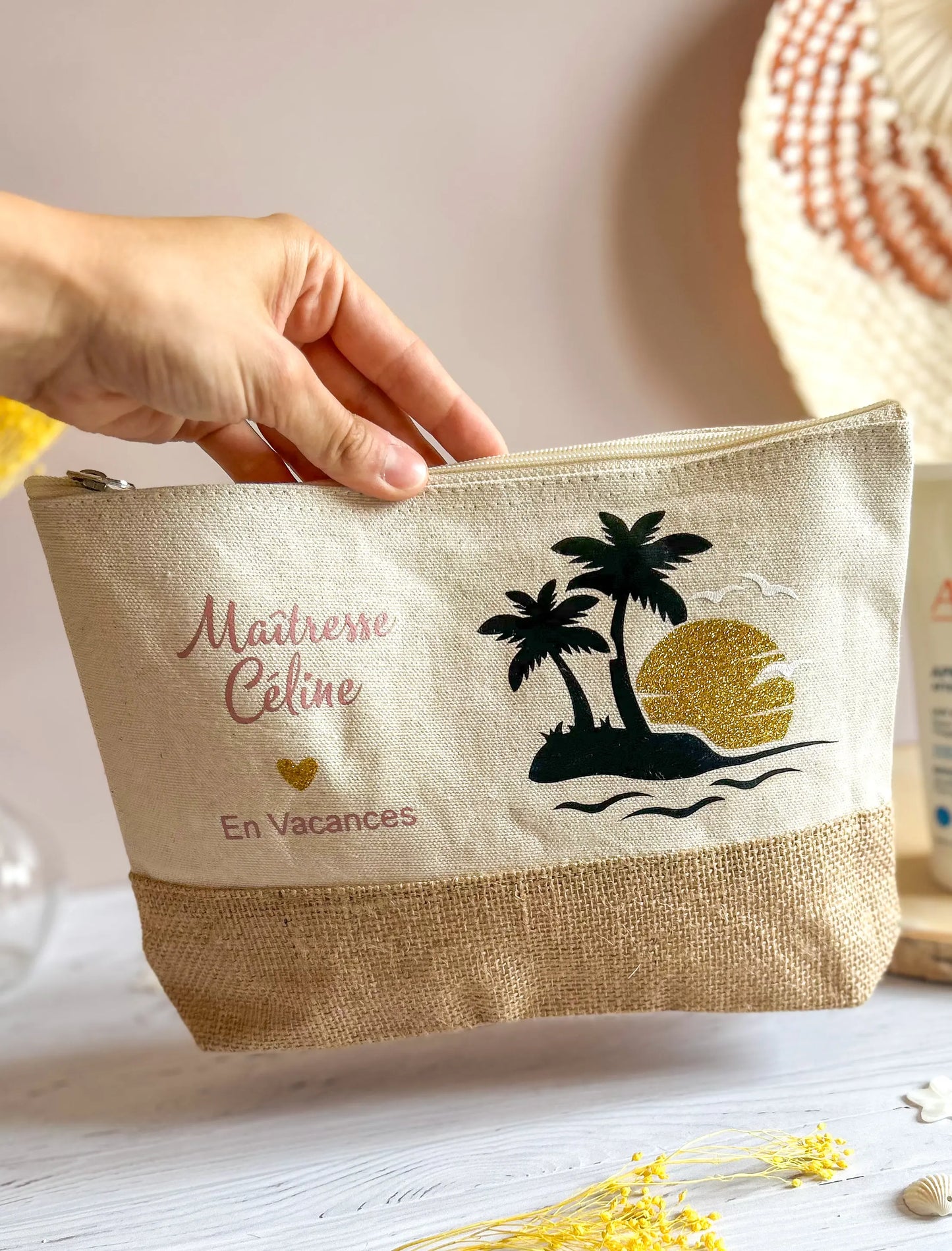 Trousse personnalisée tenue à la main, avec motif palmier et fond en toile de jute, cadeau de fin d’année pour maîtresse.