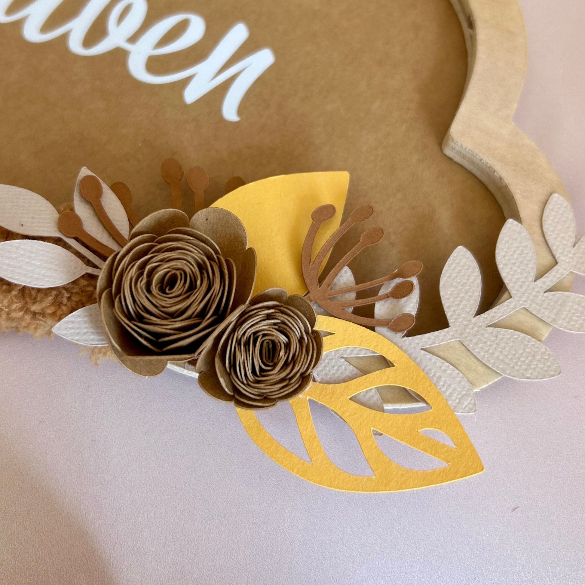 Détail des fleurs en papier réalisées à la main dans des teintes chaudes : marron, ocre, beige sable, idéales pour la décoration chambre bébé.